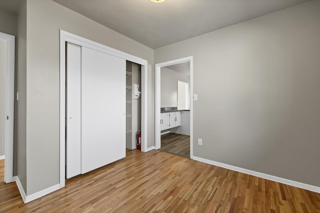 unfurnished bedroom with baseboards, a closet, and light wood-style floors