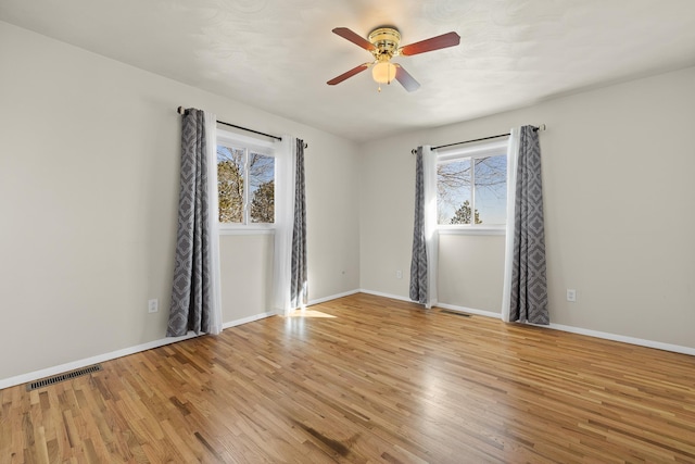 spare room featuring light wood-type flooring, visible vents, and baseboards