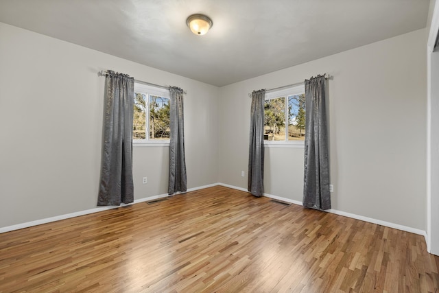 empty room featuring visible vents, baseboards, and wood finished floors