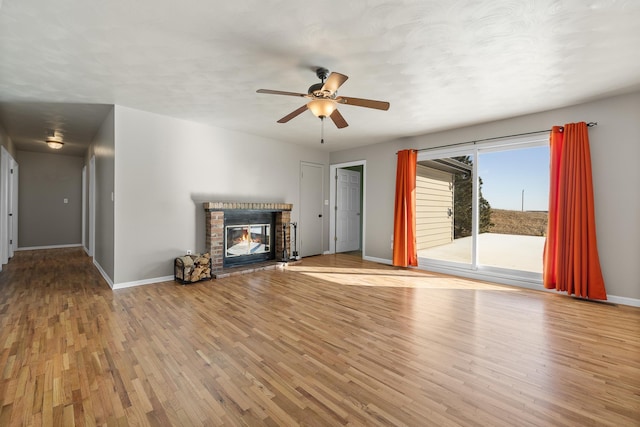 unfurnished living room featuring light wood-type flooring, a fireplace, baseboards, and ceiling fan