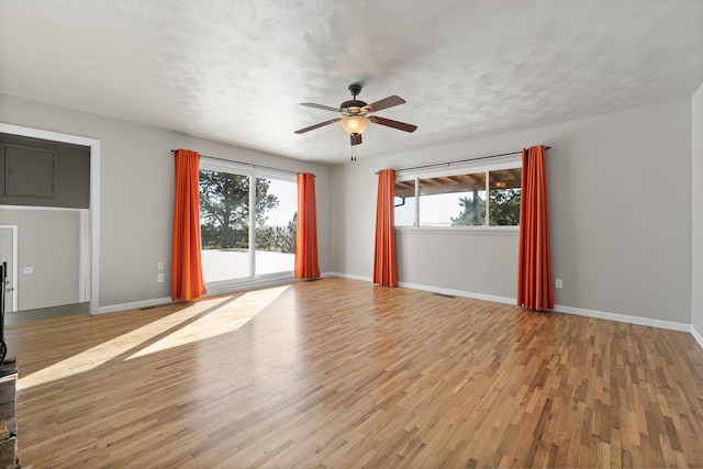 unfurnished living room with light wood finished floors, plenty of natural light, and baseboards