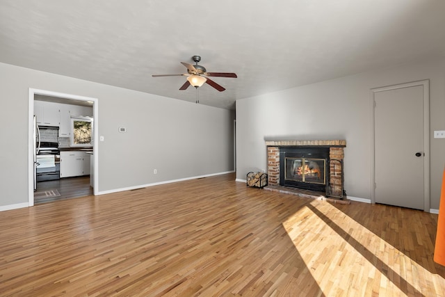 unfurnished living room with light wood finished floors, a fireplace, and baseboards