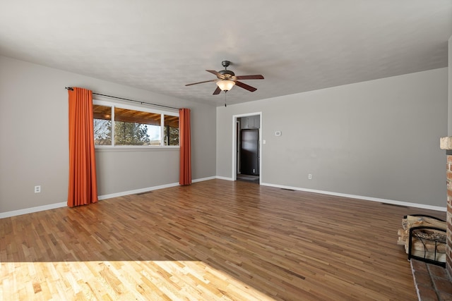 empty room with a ceiling fan, visible vents, baseboards, and wood finished floors