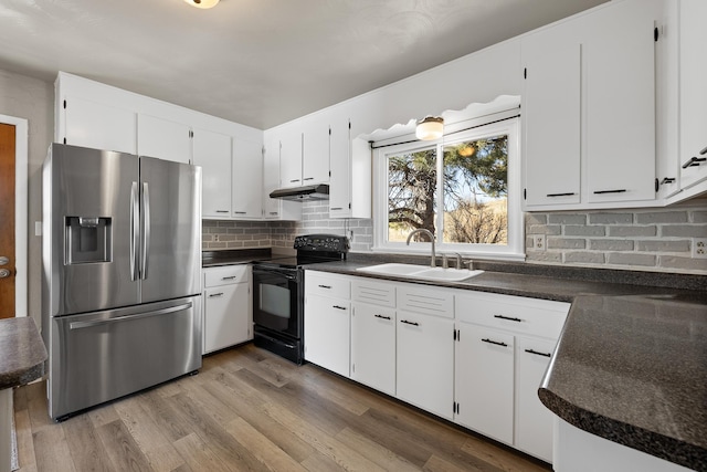 kitchen featuring a sink, dark countertops, stainless steel fridge, and black range with electric stovetop