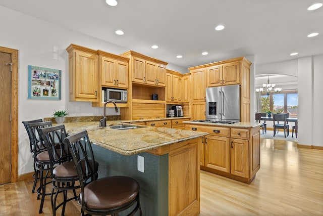 kitchen with arched walkways, stainless steel appliances, a sink, a peninsula, and a kitchen breakfast bar