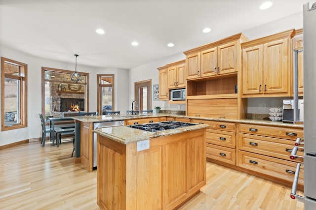 kitchen featuring a kitchen island, appliances with stainless steel finishes, a breakfast bar area, a peninsula, and hanging light fixtures