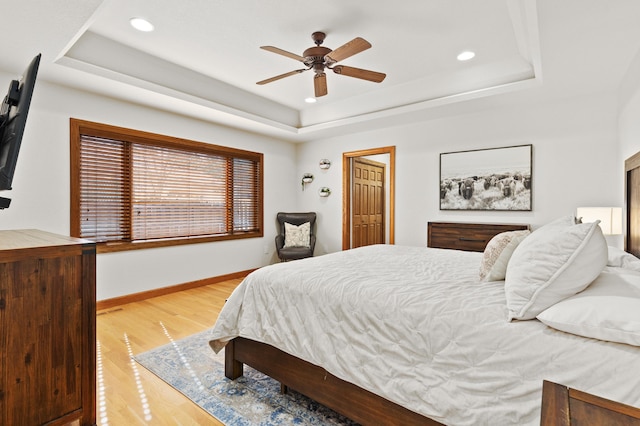 bedroom featuring a tray ceiling, baseboards, light wood finished floors, and recessed lighting