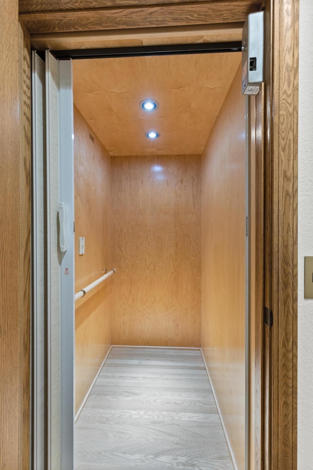 interior details with recessed lighting, elevator, and wood walls