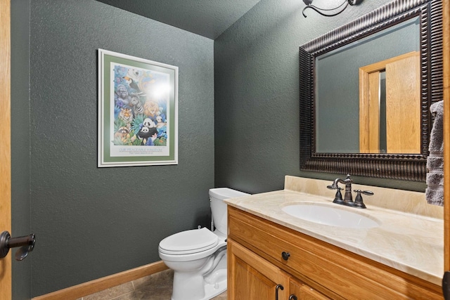 half bath featuring a textured wall, toilet, vanity, baseboards, and tile patterned floors