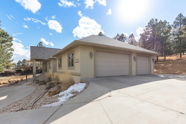 view of home's exterior featuring a garage, roof with shingles, driveway, and stucco siding