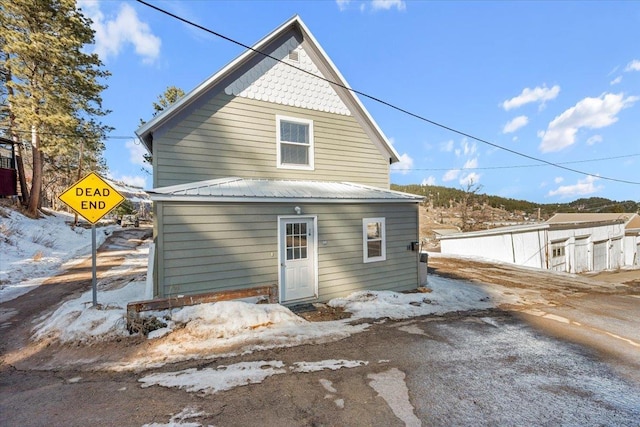 snow covered rear of property featuring metal roof