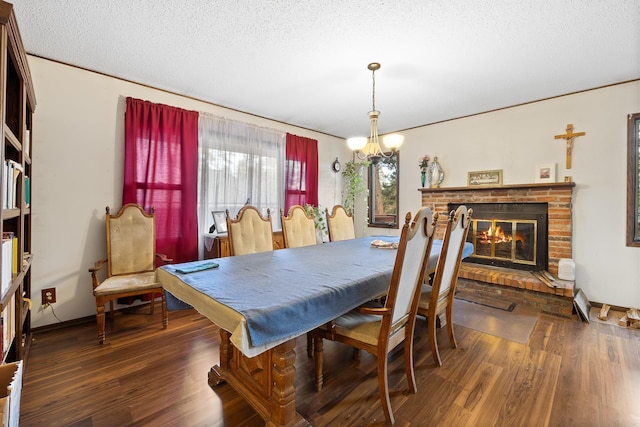 dining room with a chandelier, a brick fireplace, a textured ceiling, and wood finished floors