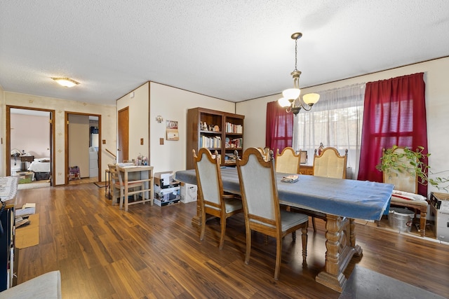 dining room featuring a notable chandelier, a textured ceiling, washer / clothes dryer, and wood finished floors