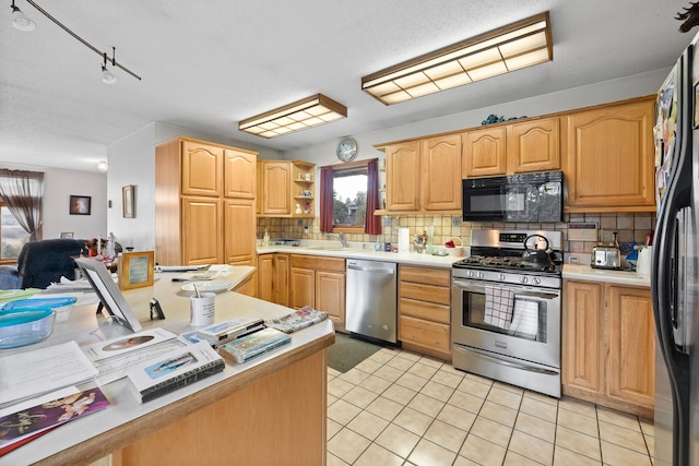 kitchen with stainless steel appliances, tasteful backsplash, light countertops, light tile patterned flooring, and a sink