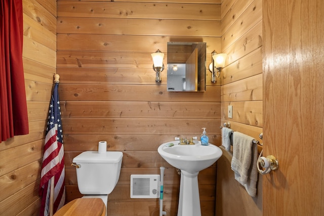 half bath featuring toilet, a sink, visible vents, and wooden walls