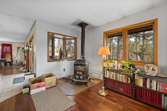 interior space with a wood stove, wood-type flooring, and a textured ceiling