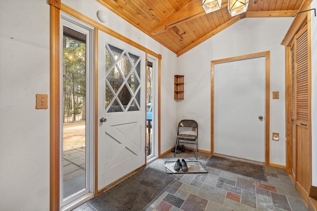 foyer entrance with vaulted ceiling with skylight, wood ceiling, baseboards, and stone tile flooring