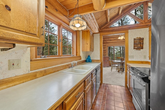 kitchen with appliances with stainless steel finishes, vaulted ceiling with beams, a sink, and wallpapered walls