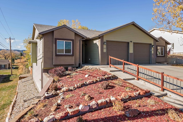 ranch-style home featuring a garage, driveway, a shingled roof, and stucco siding