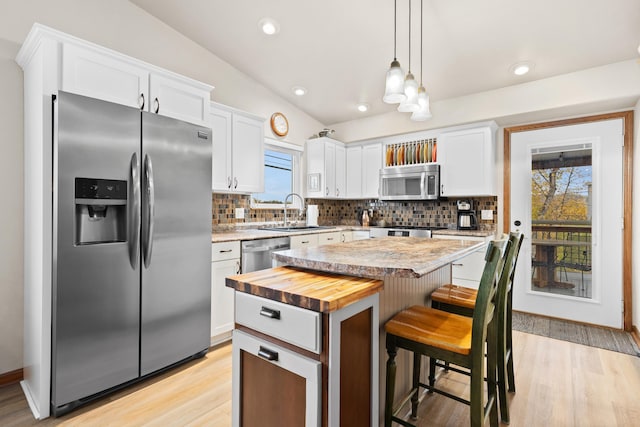 kitchen featuring appliances with stainless steel finishes, white cabinetry, a sink, and a kitchen island