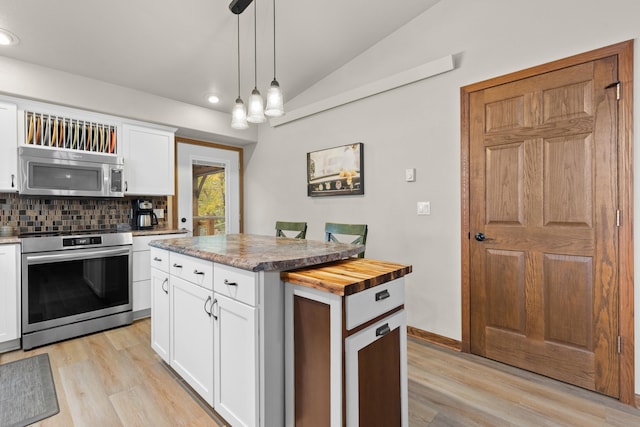 kitchen with light wood finished floors, tasteful backsplash, vaulted ceiling, stainless steel appliances, and pendant lighting