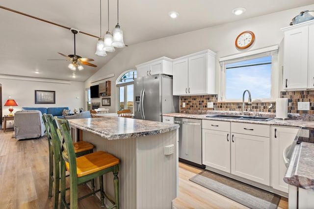 kitchen featuring white cabinets, stainless steel appliances, a sink, and a center island