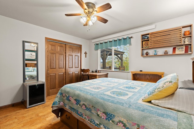 bedroom featuring ceiling fan, a closet, light wood-style flooring, and baseboards