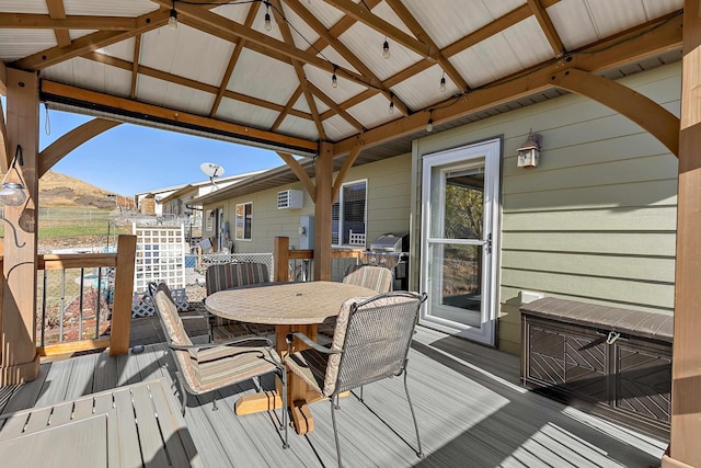 wooden terrace featuring outdoor dining area, grilling area, and a gazebo