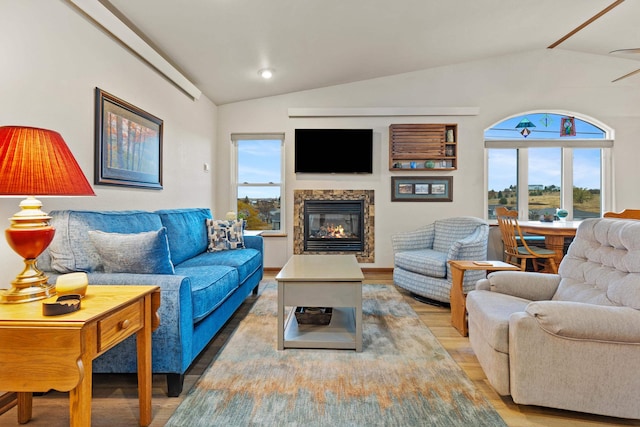 living area featuring lofted ceiling, a glass covered fireplace, and light wood finished floors