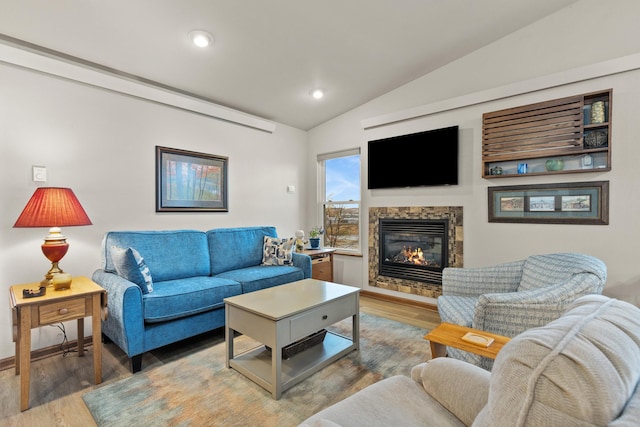 living room with vaulted ceiling, recessed lighting, a glass covered fireplace, and light wood-style floors