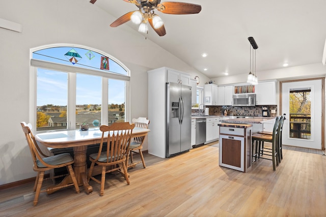 kitchen with stainless steel appliances, white cabinetry, a kitchen island, and light wood finished floors