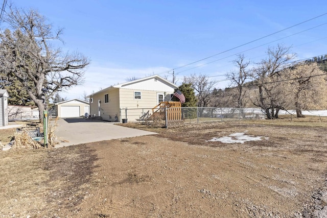 exterior space featuring dirt driveway, fence, a detached garage, and an outbuilding