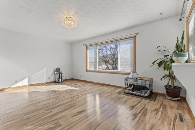 interior space featuring an inviting chandelier, visible vents, baseboards, and wood finished floors