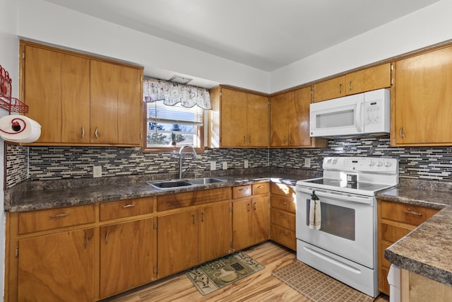 kitchen with dark countertops, white appliances, tasteful backsplash, and a sink