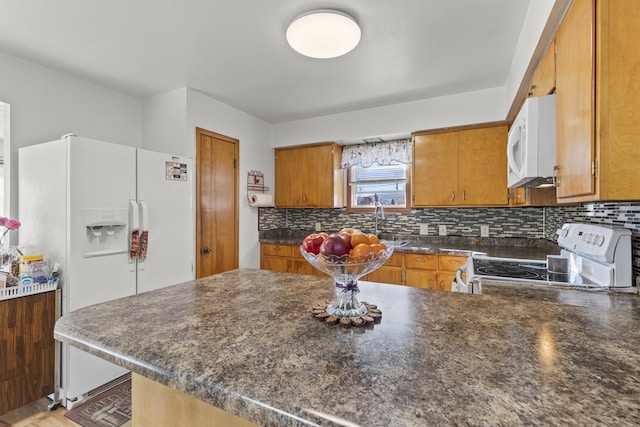 kitchen with white appliances, dark countertops, backsplash, and brown cabinets