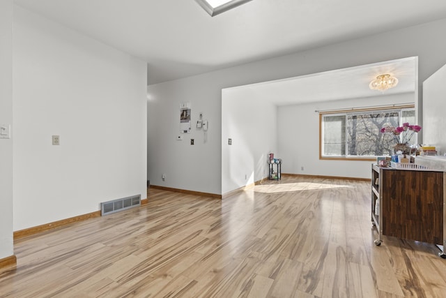 living area featuring baseboards, visible vents, and light wood-style floors