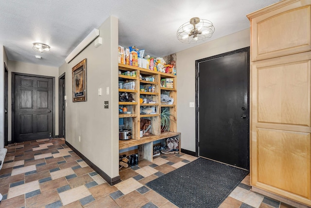 entrance foyer featuring a textured ceiling, stone finish flooring, and baseboards