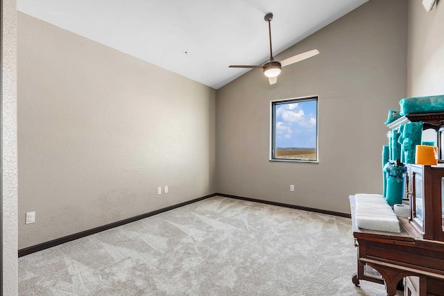 interior space with carpet floors, baseboards, vaulted ceiling, and a ceiling fan