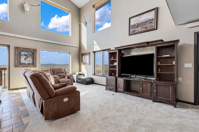 living room featuring carpet floors, a towering ceiling, and baseboards