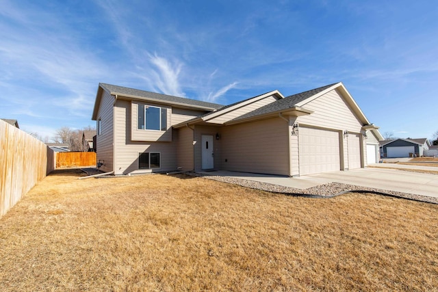 view of front of house featuring a front yard, concrete driveway, fence, and an attached garage