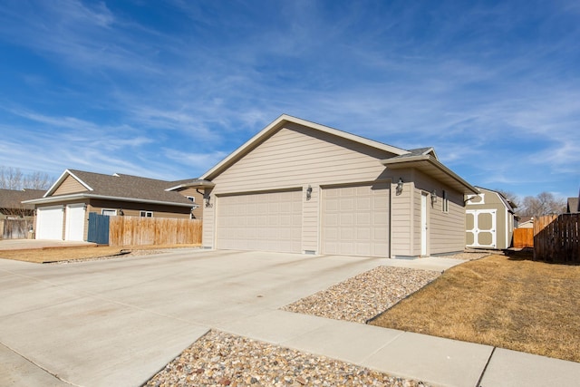 view of side of property featuring an outbuilding, an attached garage, fence, a shed, and driveway