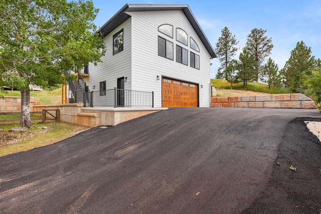 view of home's exterior featuring a garage, fence, stairway, and aphalt driveway