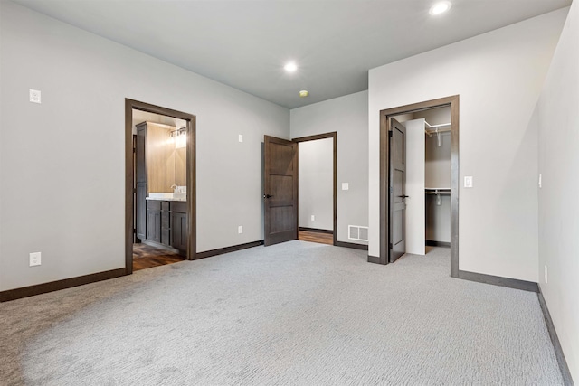 unfurnished bedroom with carpet, visible vents, a walk in closet, and baseboards