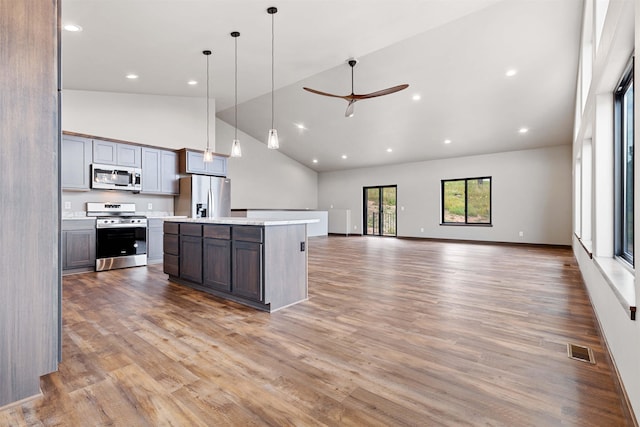 kitchen with stainless steel appliances, light countertops, visible vents, a ceiling fan, and a kitchen island