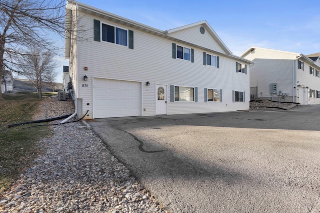 view of front facade featuring a garage, central AC unit, and aphalt driveway