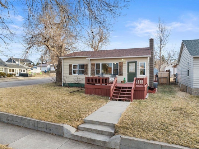 bungalow featuring a deck, a front yard, fence, and a chimney