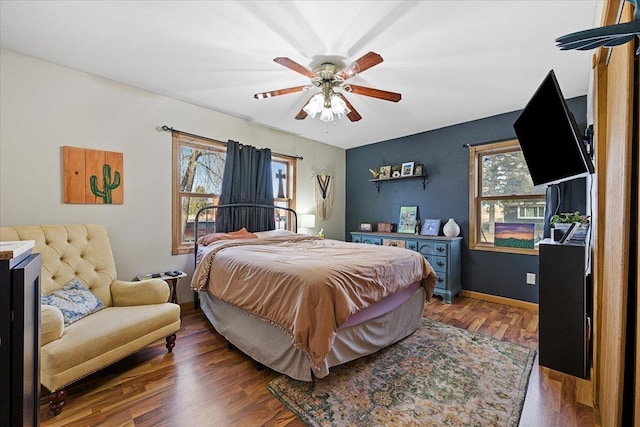 bedroom with a ceiling fan, multiple windows, baseboards, and wood finished floors