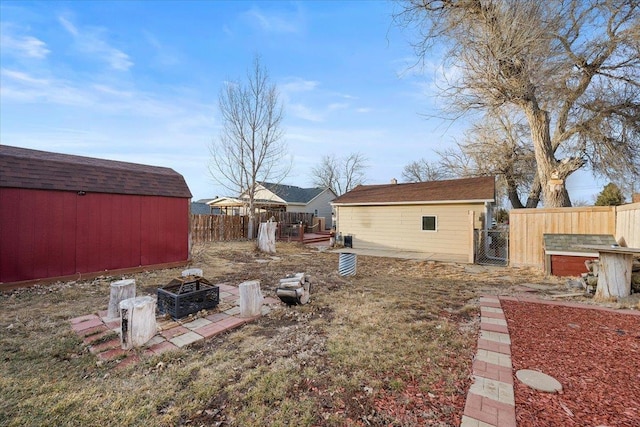 view of yard featuring an outbuilding, a gate, fence, and a fire pit