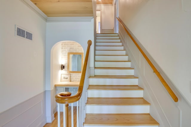 stairs with visible vents, wainscoting, ornamental molding, wood finished floors, and a decorative wall