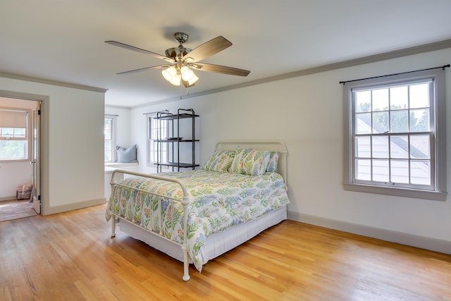 bedroom with ornamental molding, light wood-style flooring, baseboards, and a ceiling fan